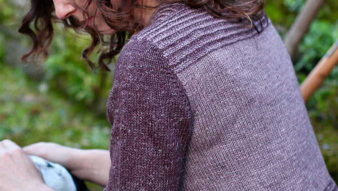 back of woman looking down, wearing pink and purple cardigan