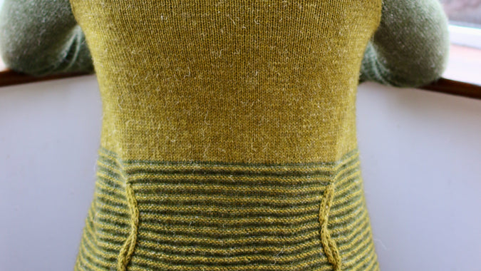 image of woman from the back, kneeling with a two colour green cardigan