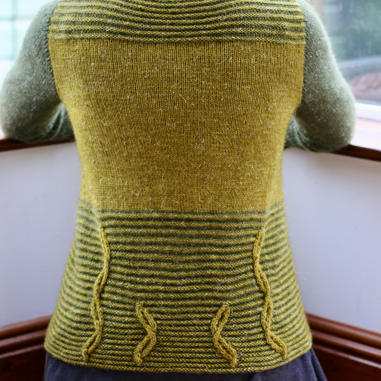 image of woman from the back, kneeling with a two colour green cardigan