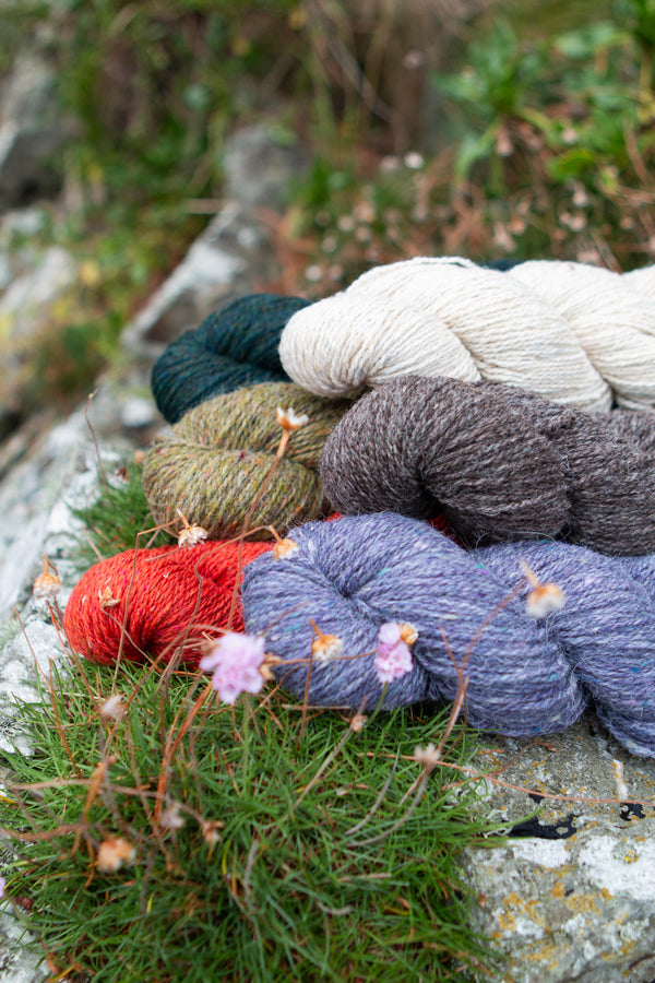 yarn on rock with flowers and grass