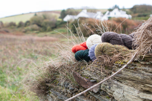 Colorful yarn skeins on a stone wall with a scenic background