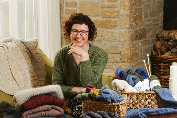 Carol Feller sat on a couch with a basked full of yarn in front of her.