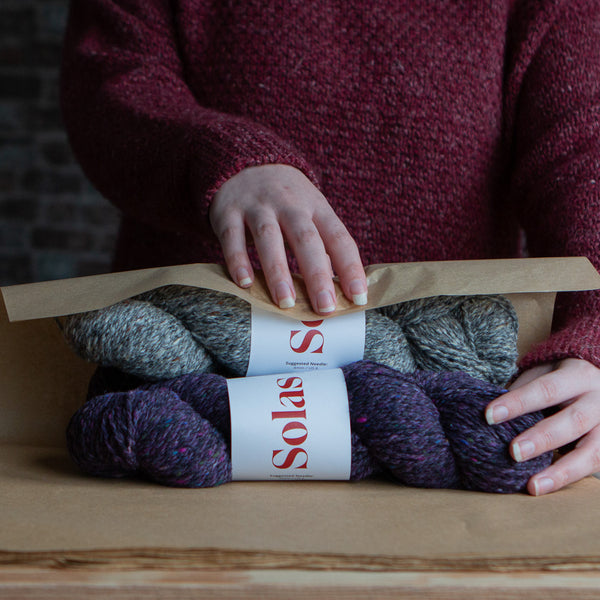 hands wrapping two skeins of yarn in brown paper